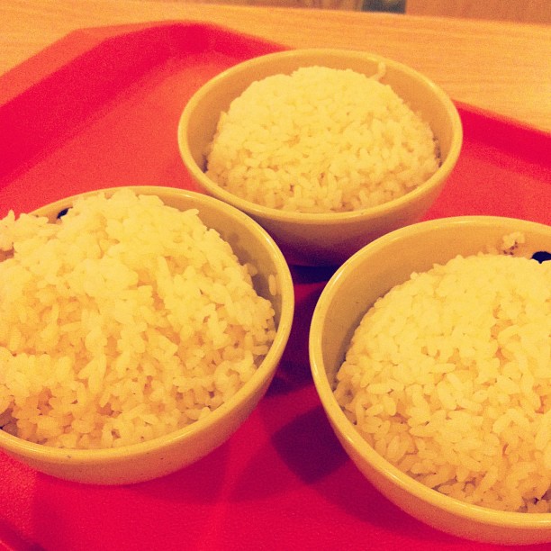 a red tray holding three bowls of rice