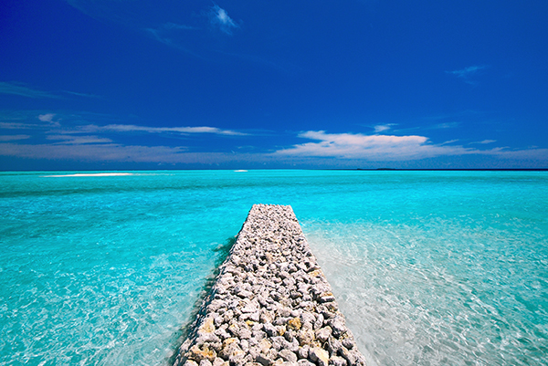 stone pier next to the ocean under a bright blue sky
