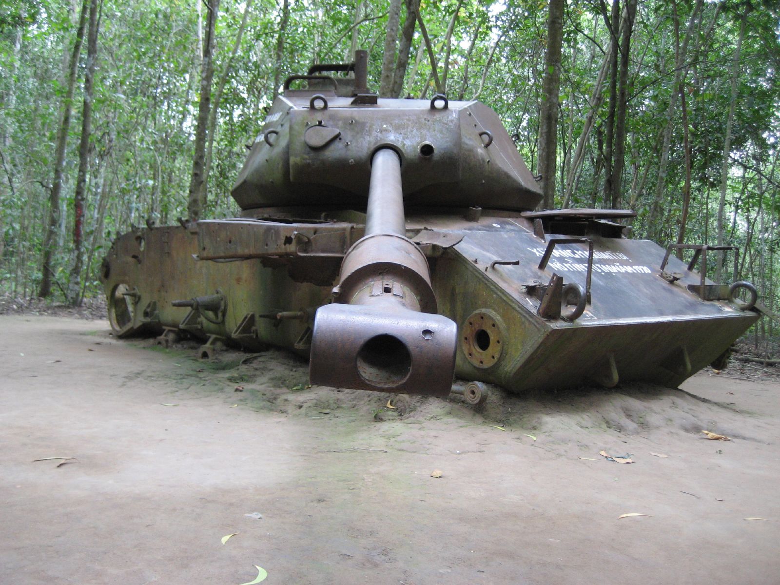a rusted tank in front of some trees