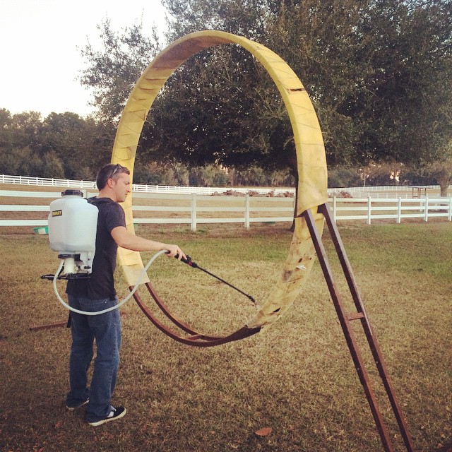 a man standing in a field spraying down a circle shape sculpture