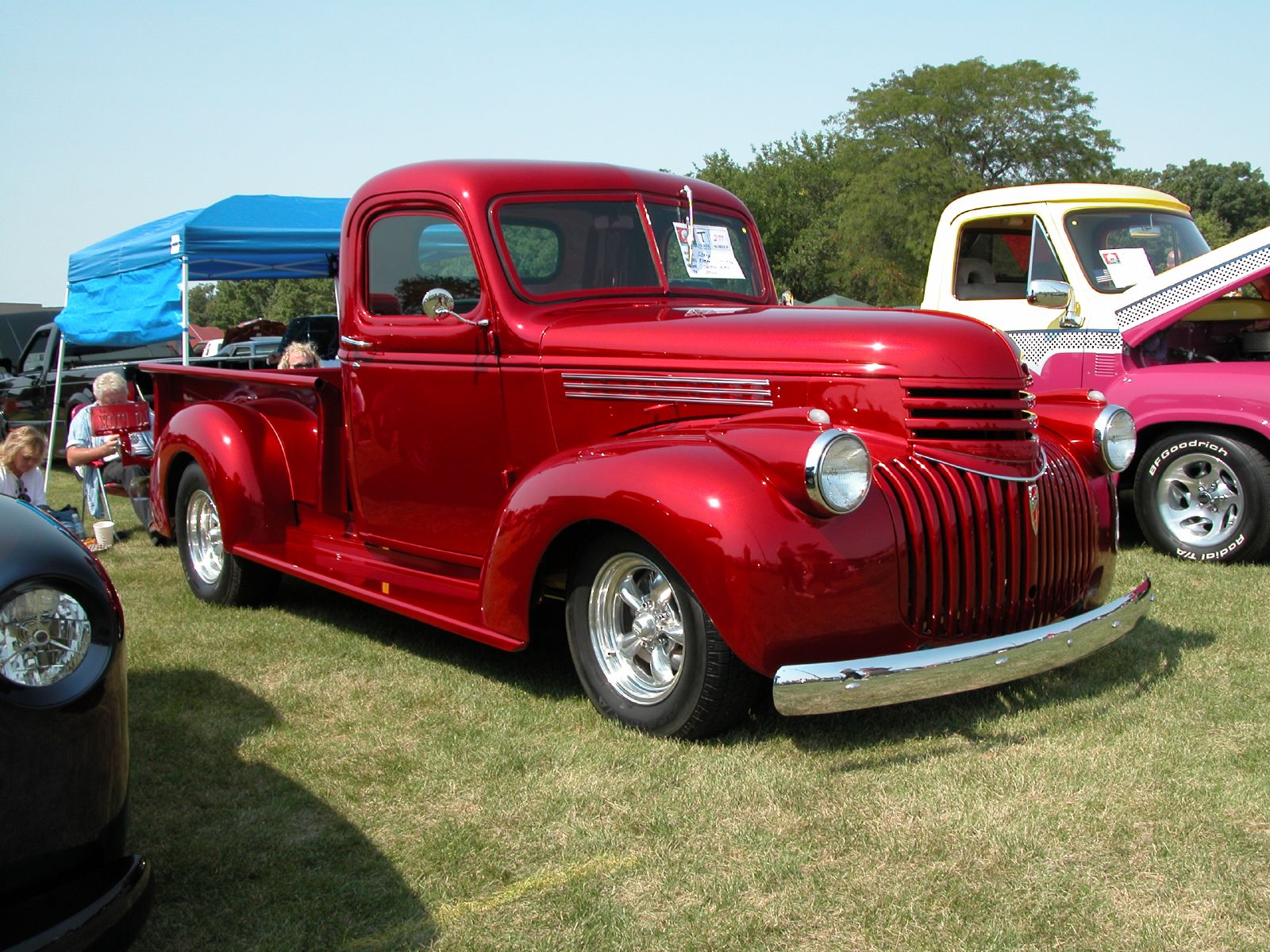 an antique red truck with people in the background