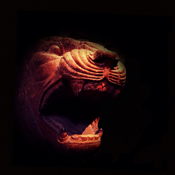 an intricately carved, wooden animal head, on display at a museum