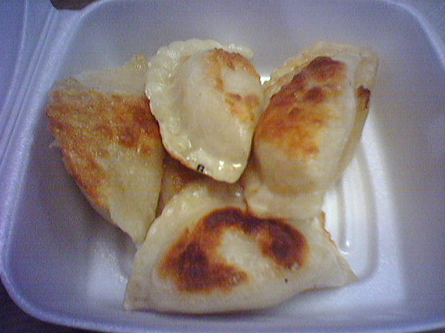 a white plate filled with dumplings and cheese