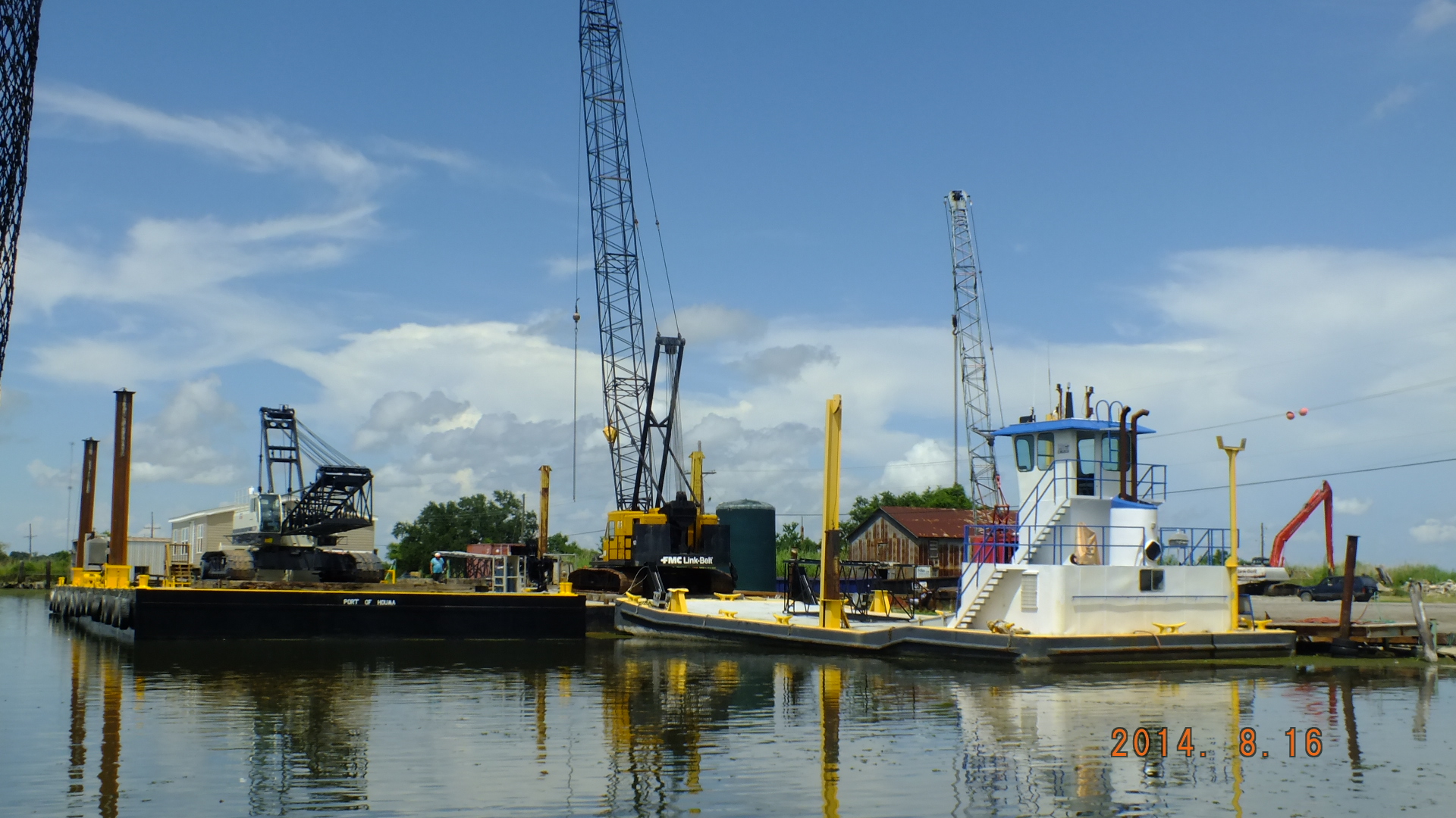 a tug boat moored with construction cranes behind it