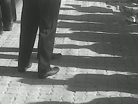 there is a black and white image of someone standing with their shadow on the pavement