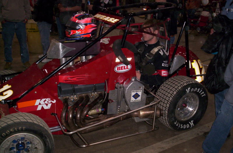 a red race car driving through a busy street