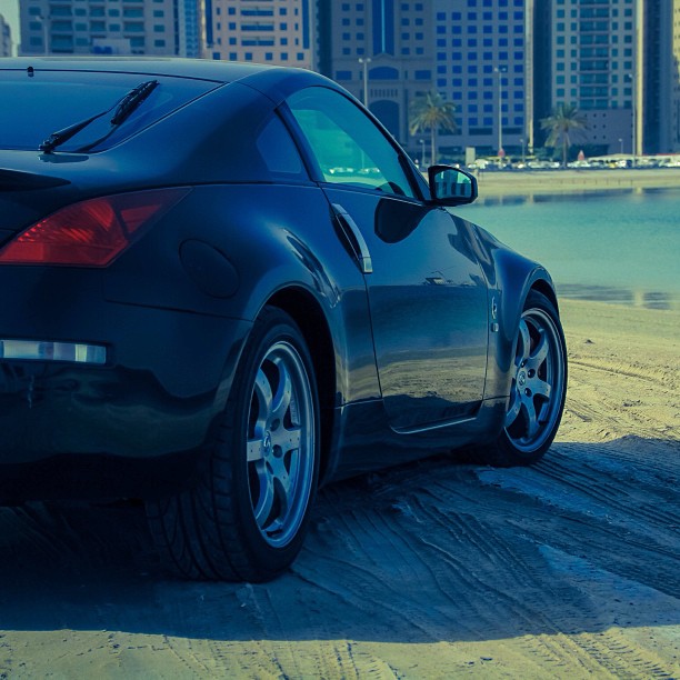 a large black sports car parked by the water