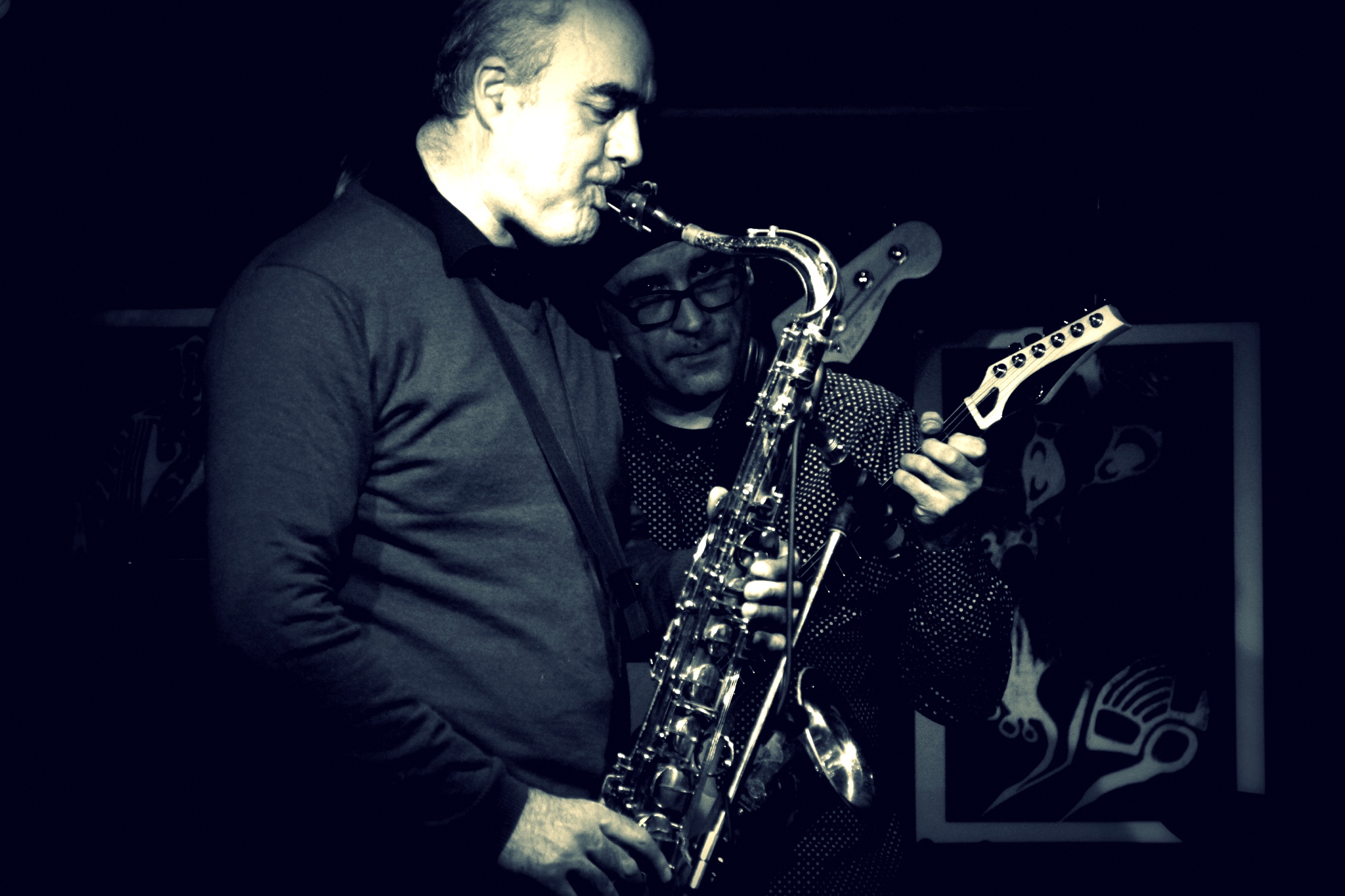 two men, one with glasses playing a saxophone