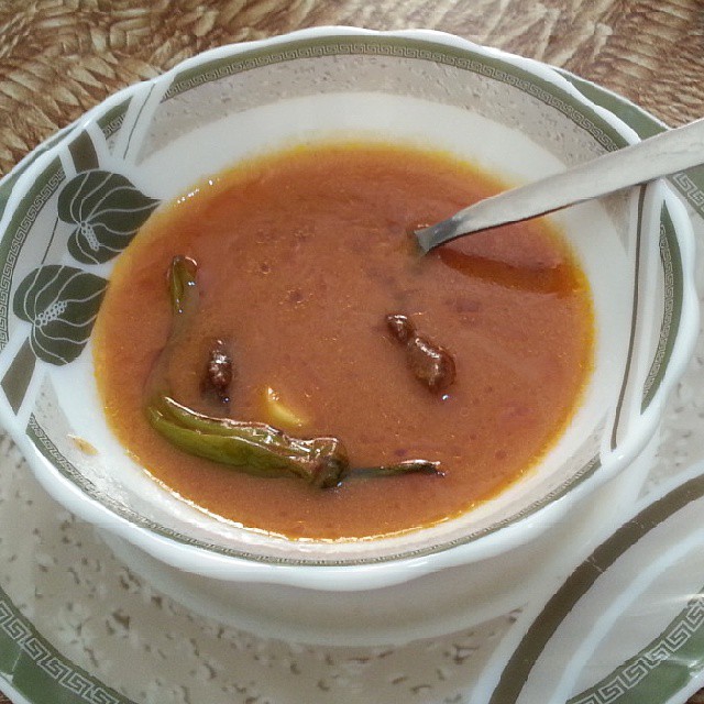 a bowl of red soup with an assortment of spices in it