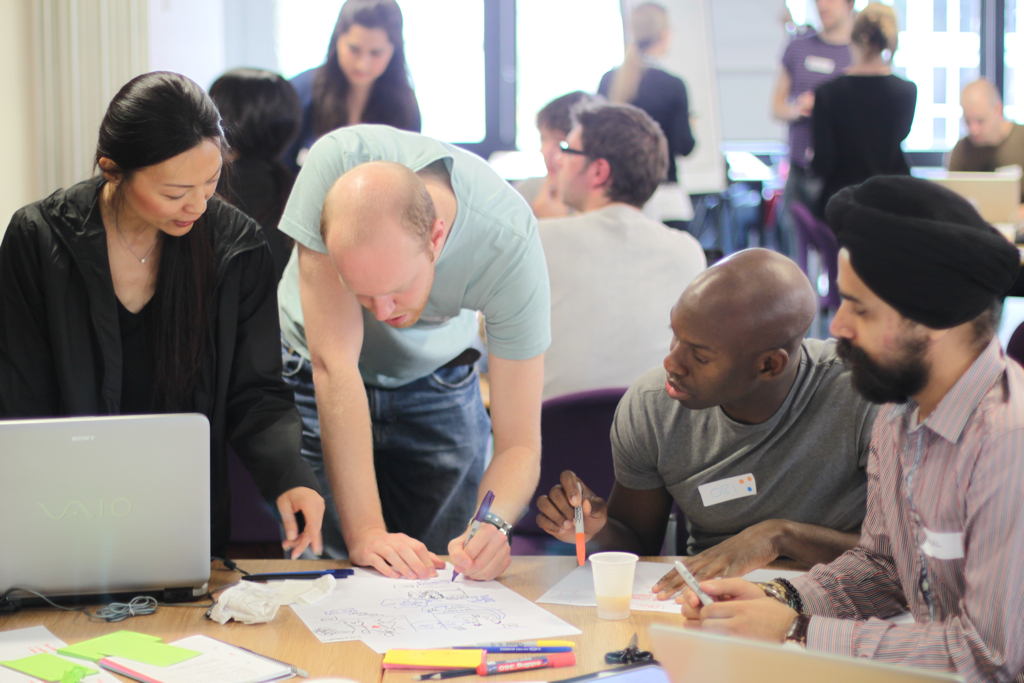 a group of people sitting at a table and working on laptops