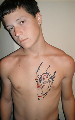 a shirtless young man with a demon tattoo on his chest