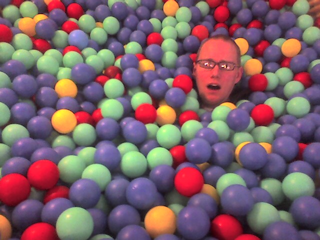 a man hiding in a pool of colored balls