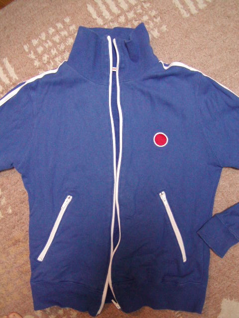 a hooded jacket that has a red dot embroidered on the side