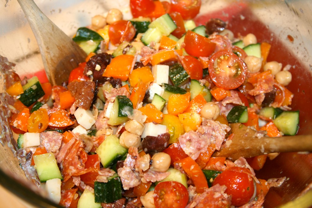 colorful vegetable salad mixed in a bowl with spoons