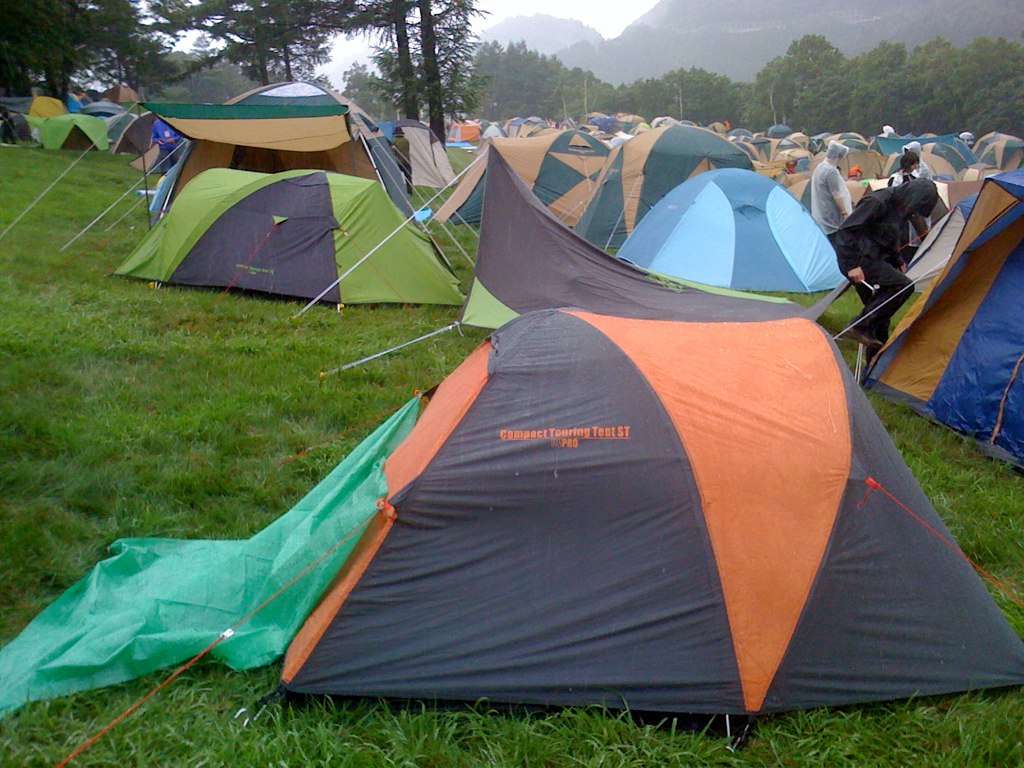 people standing in the grass near several tents