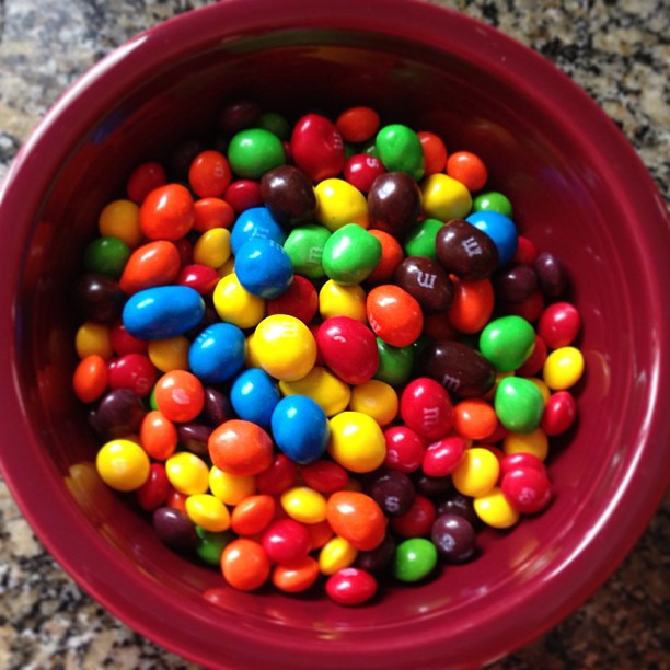 many colorful candy candy beans sit in a red bowl