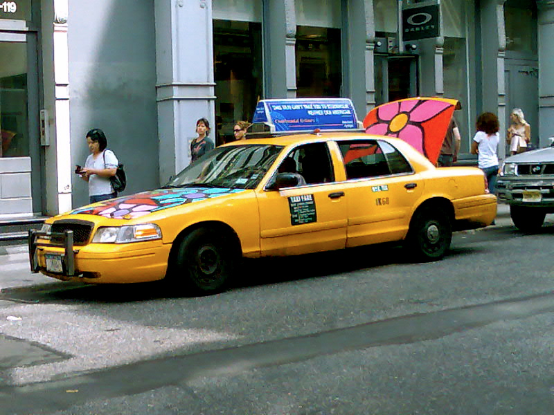 a taxi with a decorated cab cab in front of some people
