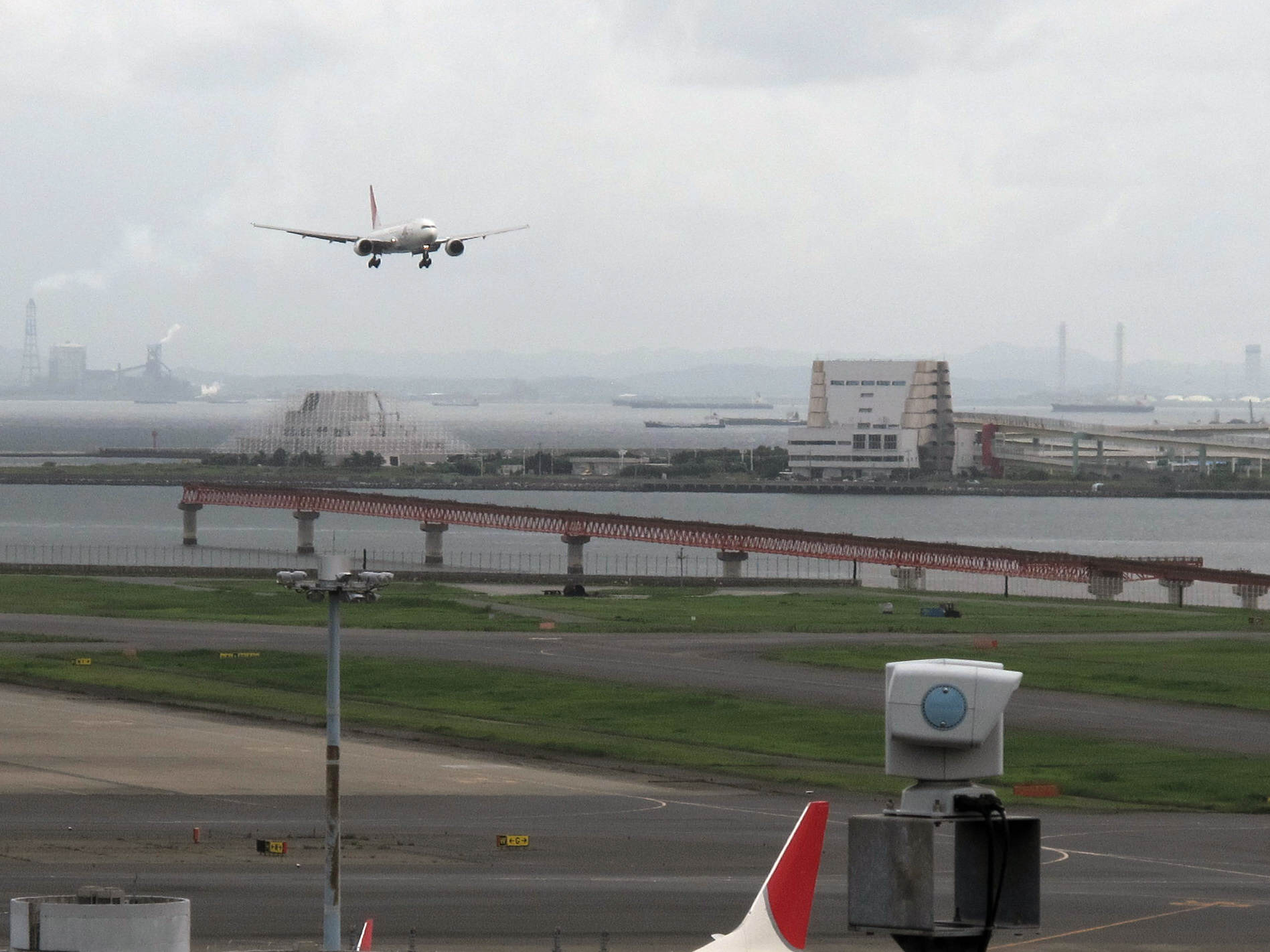 a small jet flying over the ground of an airport