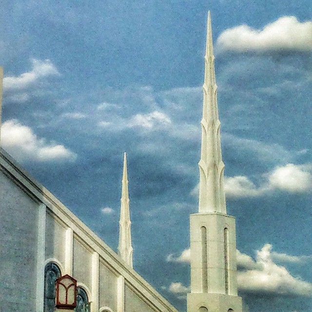 a church with a tall steeple is silhouetted against the cloudy sky