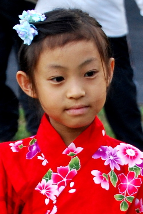 the young child wears a red chinese dress with flowers on it