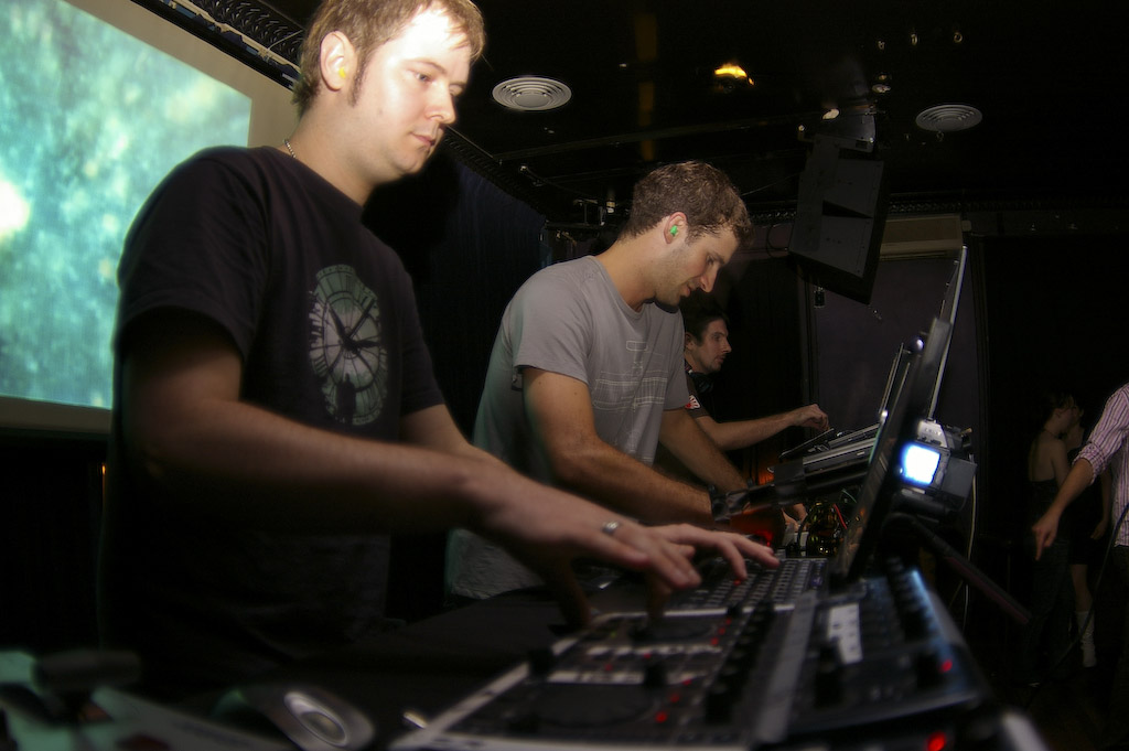 two men are operating keyboards in front of a laptop