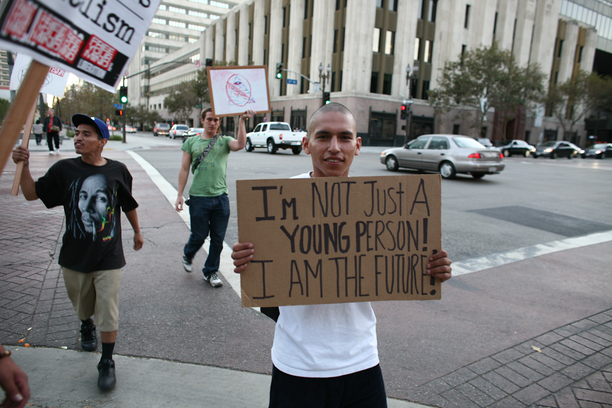 young man holding sign on the street, protesting