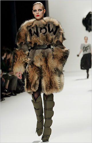 a woman in a fur jacket and boots on the runway