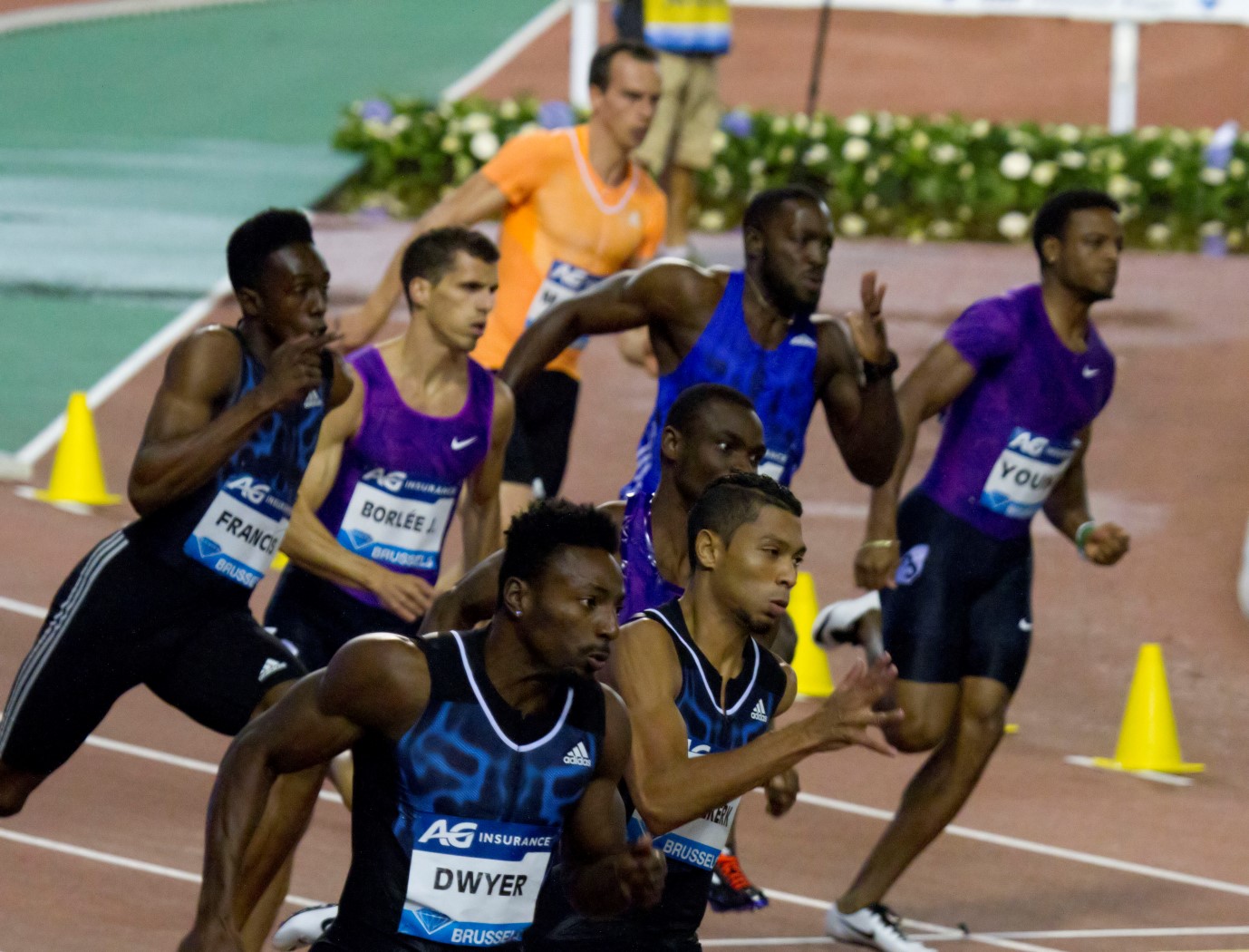 a group of men racing down a track in race uniforms