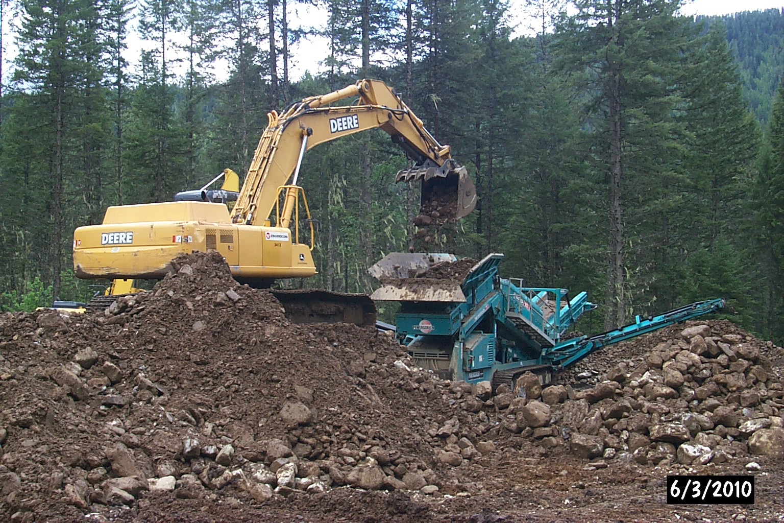 a large yellow and black machine digging dirt into a pile