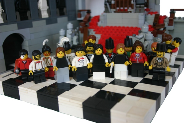 several lego figurines in different clothes are arranged on a black and white checkerboard table