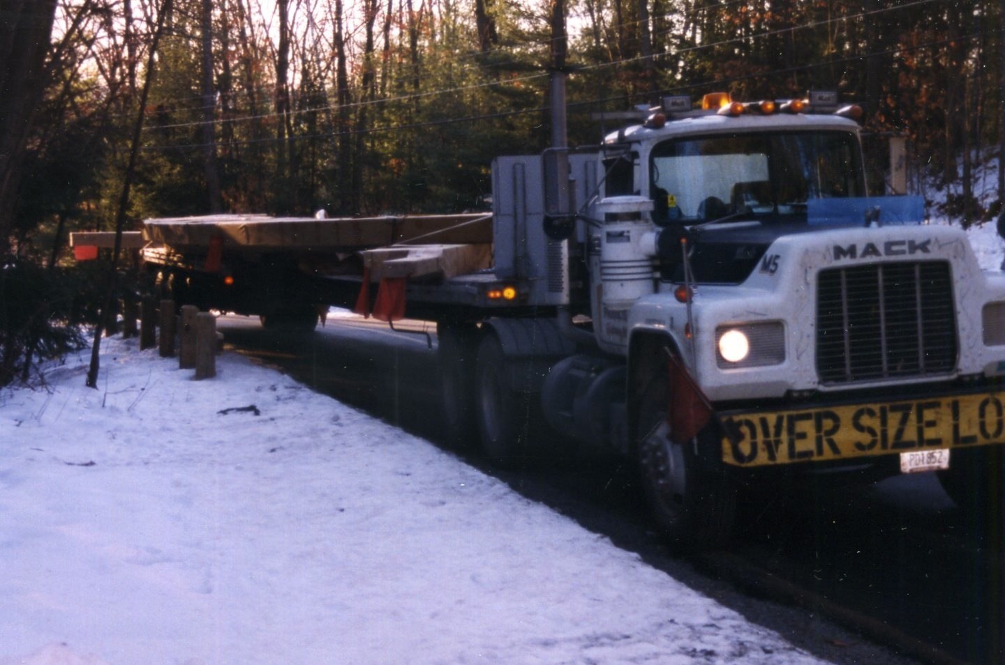 large load truck in snow at a wooded clearing