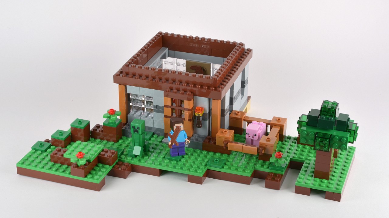 a lego model of a house, with a couple standing near the door