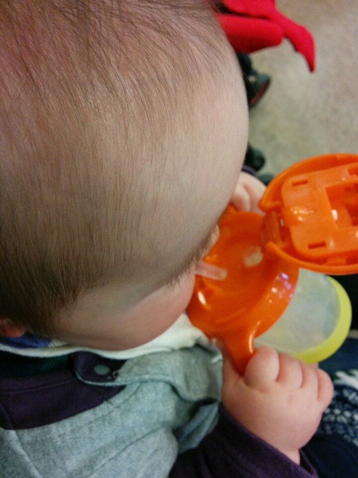 a baby is holding a plastic orange object in his mouth