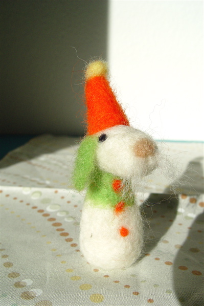 a wool toy with a tiny green tie and white and orange hat