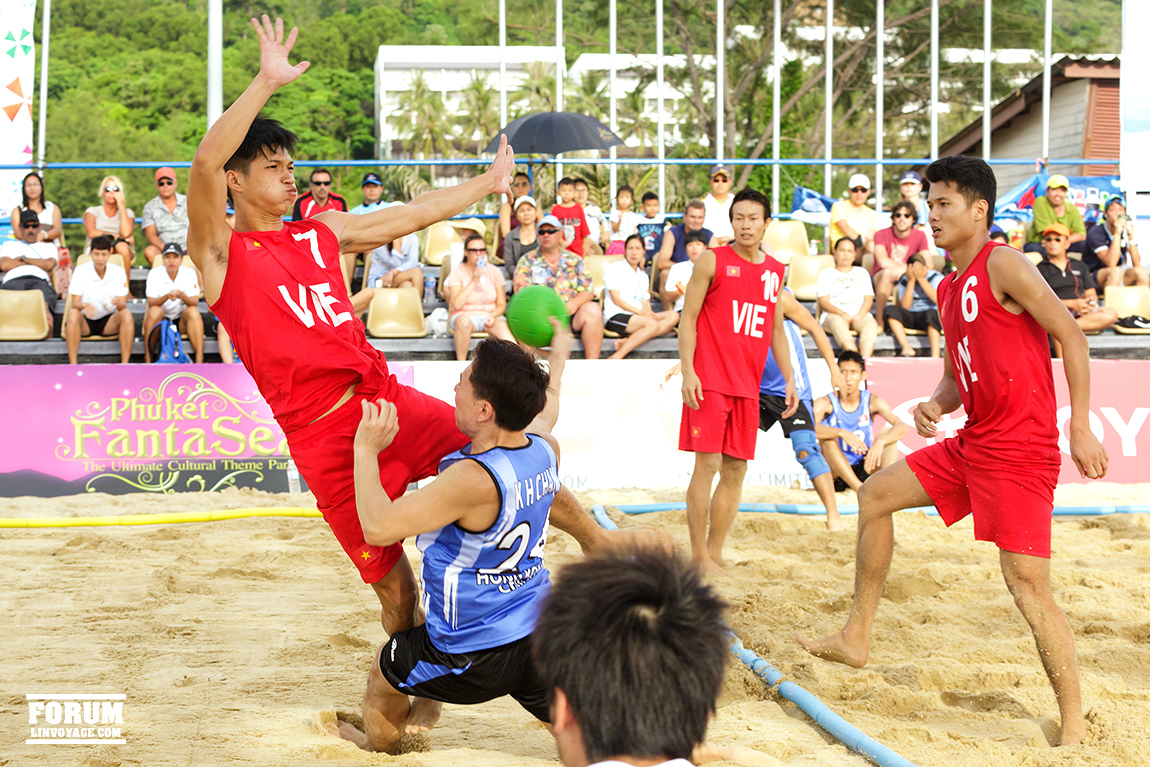 a group of people on sand playing with a frisbee