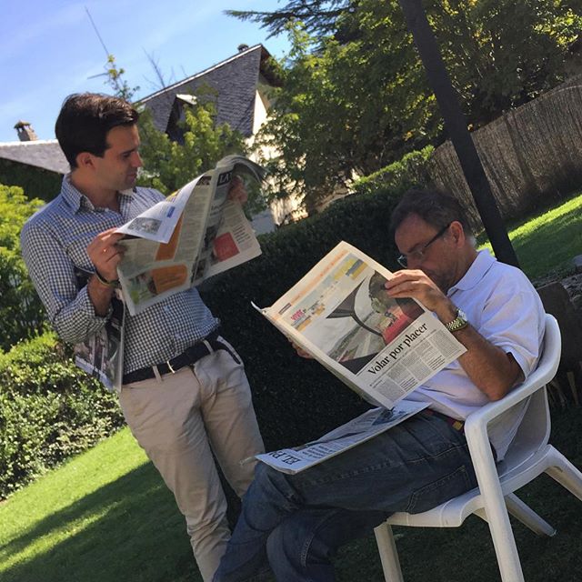 man reading the newspaper in the backyard with his friend