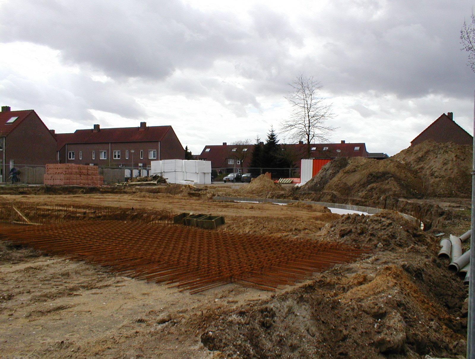 two large red brick buildings sitting near an unfinished street