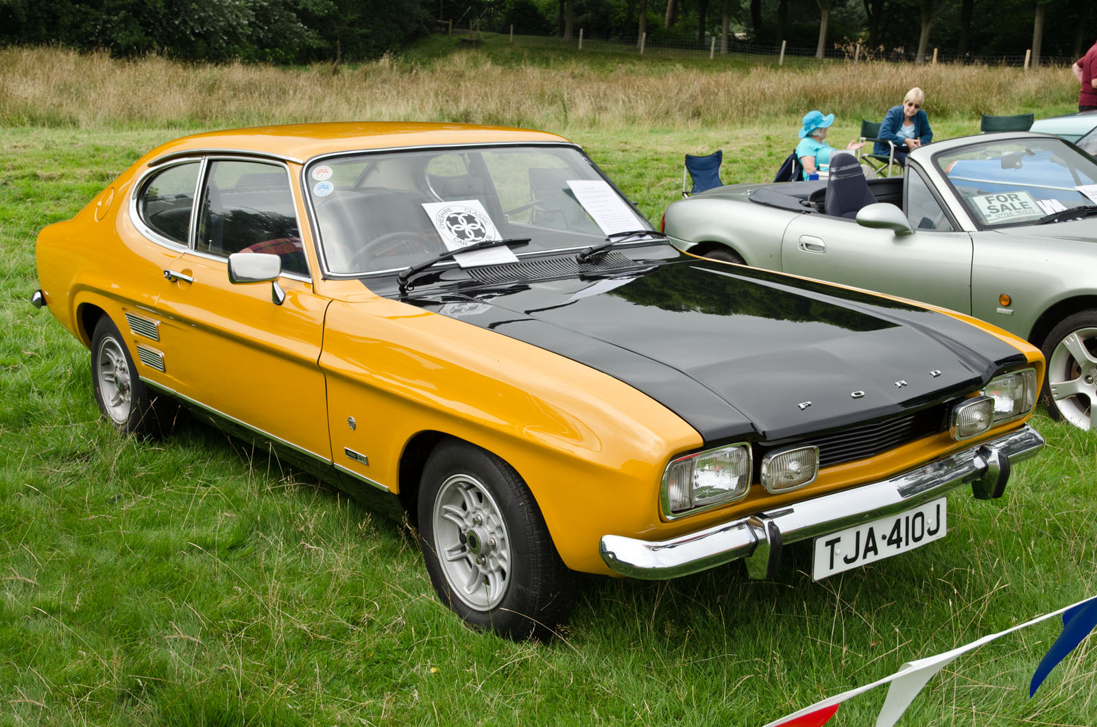 a yellow car parked in a grassy field