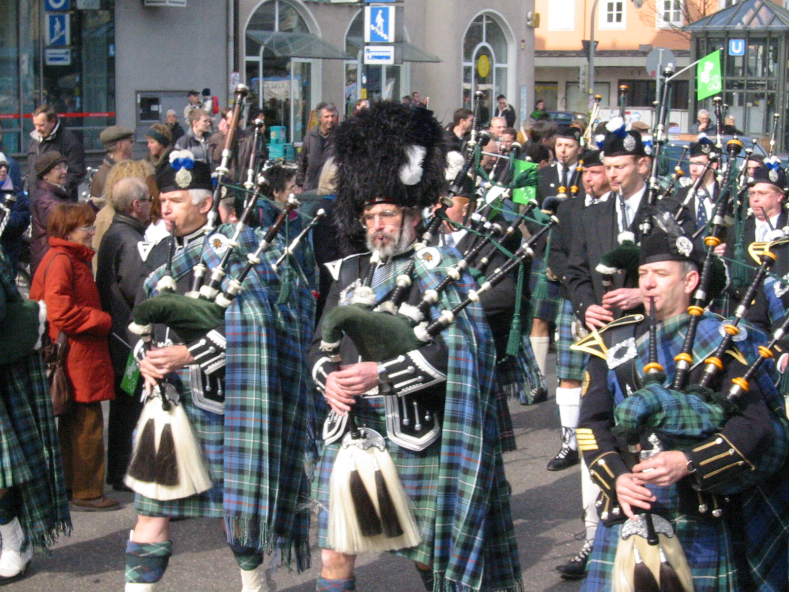 people in kilts on the street playing instruments