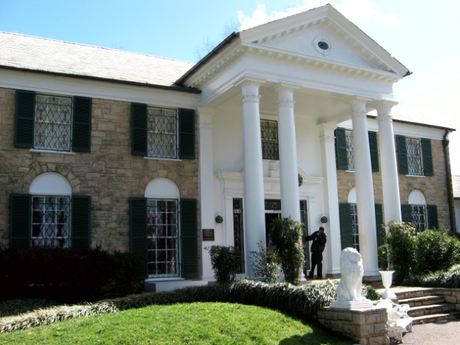 the front facade of a large white house with green shutters
