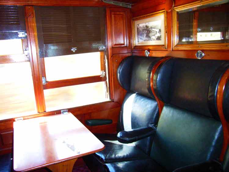 a dining car with a wood paneled wall and leather chairs