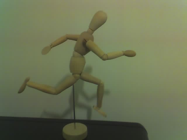a wooden doll in motion standing on a white object