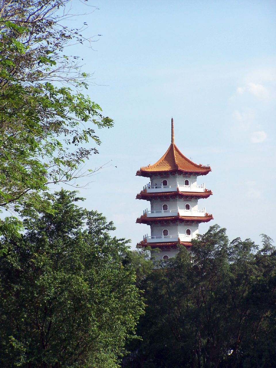 a tall white pagoda in the middle of the forest