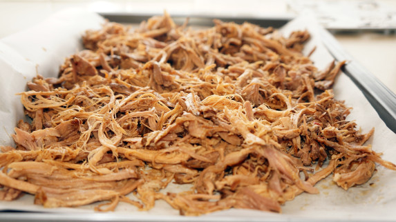 shredded pork is in a metal tray with a spoon