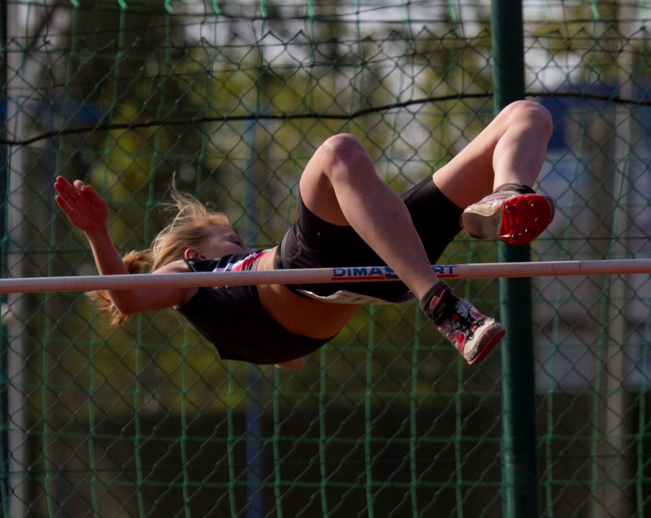 a woman on a track in the middle of doing a high jump