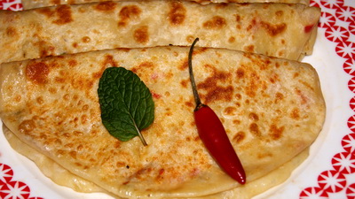 two quesadillas sit on a plate with green leaves