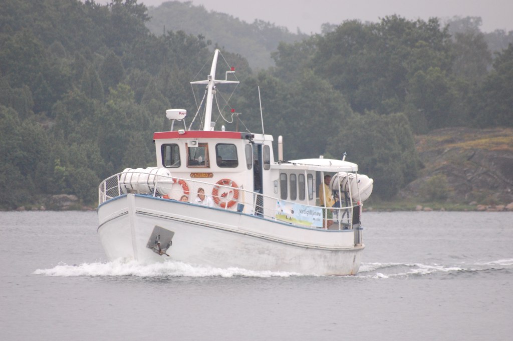 a boat traveling across a lake in front of trees