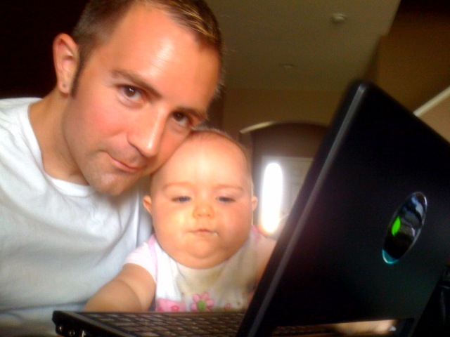 a man holding a baby next to a laptop