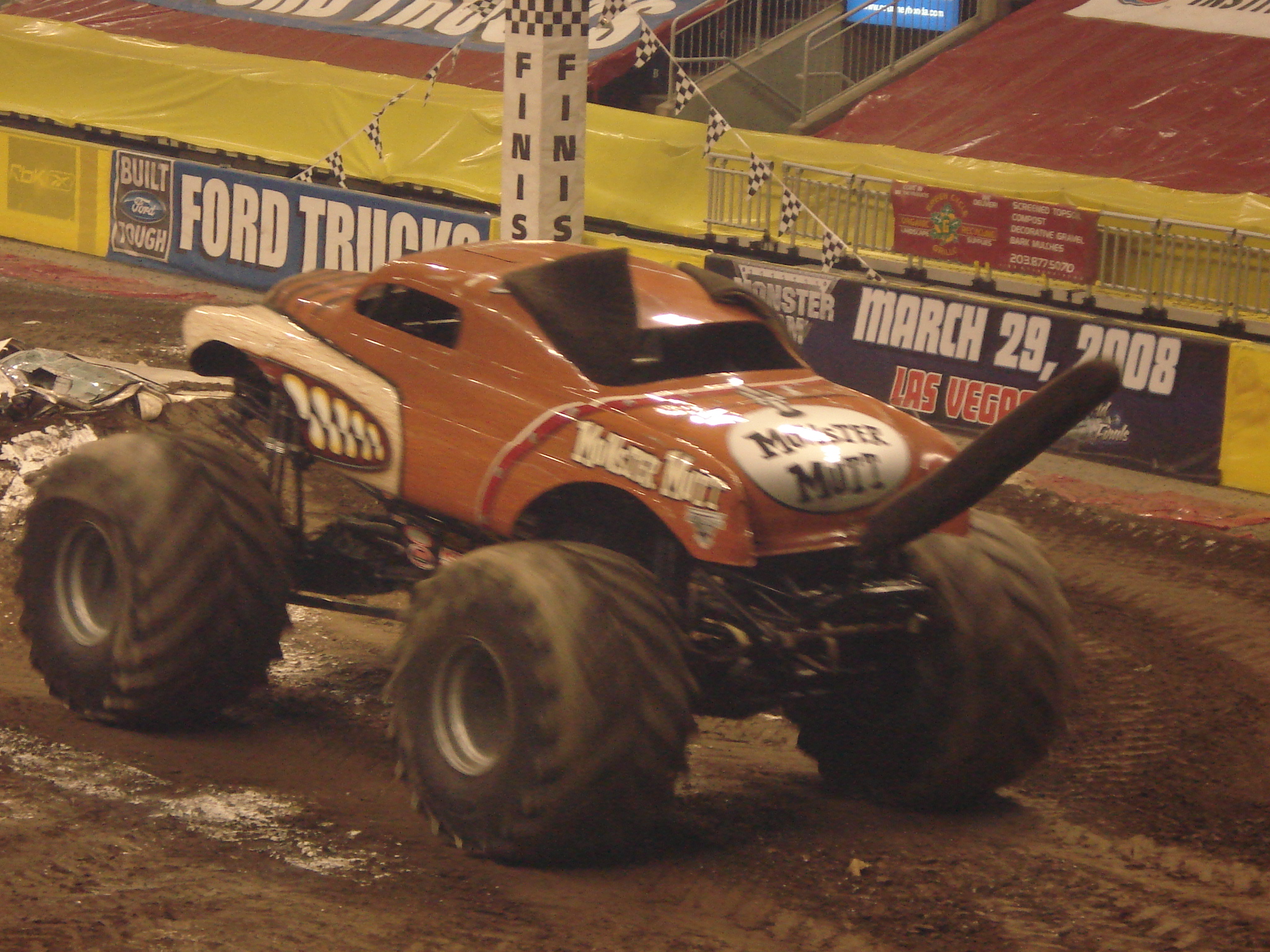 two large, off - road trucks are doing tricks in an arena