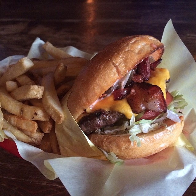 a bacon burger on top of a wooden table